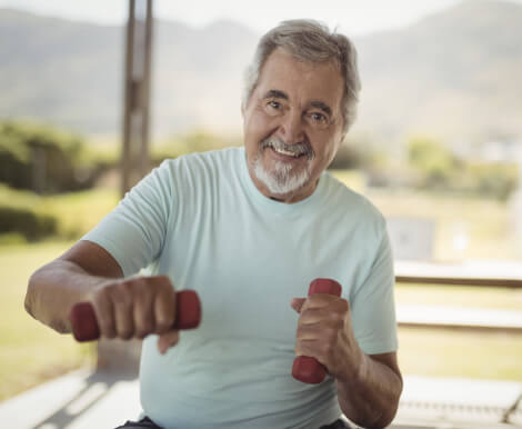 Smiling Elderly Man Exercising With Weights at Independent Living Facility Smiling Elderly Man Exercising With Weights at Independent Living Facility