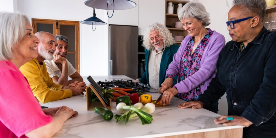 Elderly Group Preparing Vegetables Together in a Modern Kitchen at an Independent Living Facility