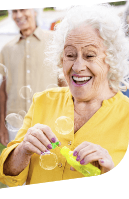 Joyful Elderly Woman Blowing Bubbles Outdoors at an Independent Living Community Joyful Elderly Woman Blowing Bubbles Outdoors at an Independent Living Community