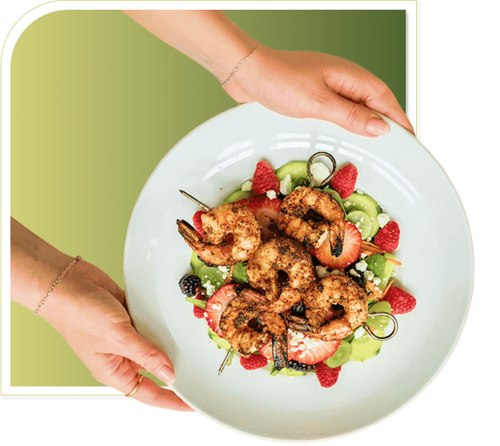 Hands Serving Plate of Grilled Shrimp Salad with Fresh Berries at Independent Living Hands Serving Plate of Grilled Shrimp Salad with Fresh Berries at Independent Living