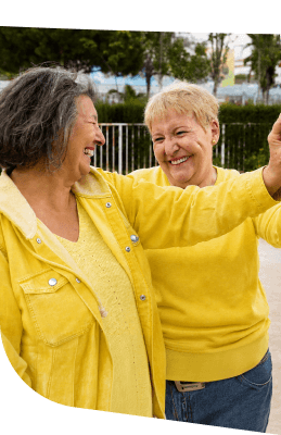 Two Joyful Elderly Women Dancing and Holding Hands Outdoors at an Independent Living Community Two Joyful Elderly Women Dancing and Holding Hands Outdoors at an Independent Living Community