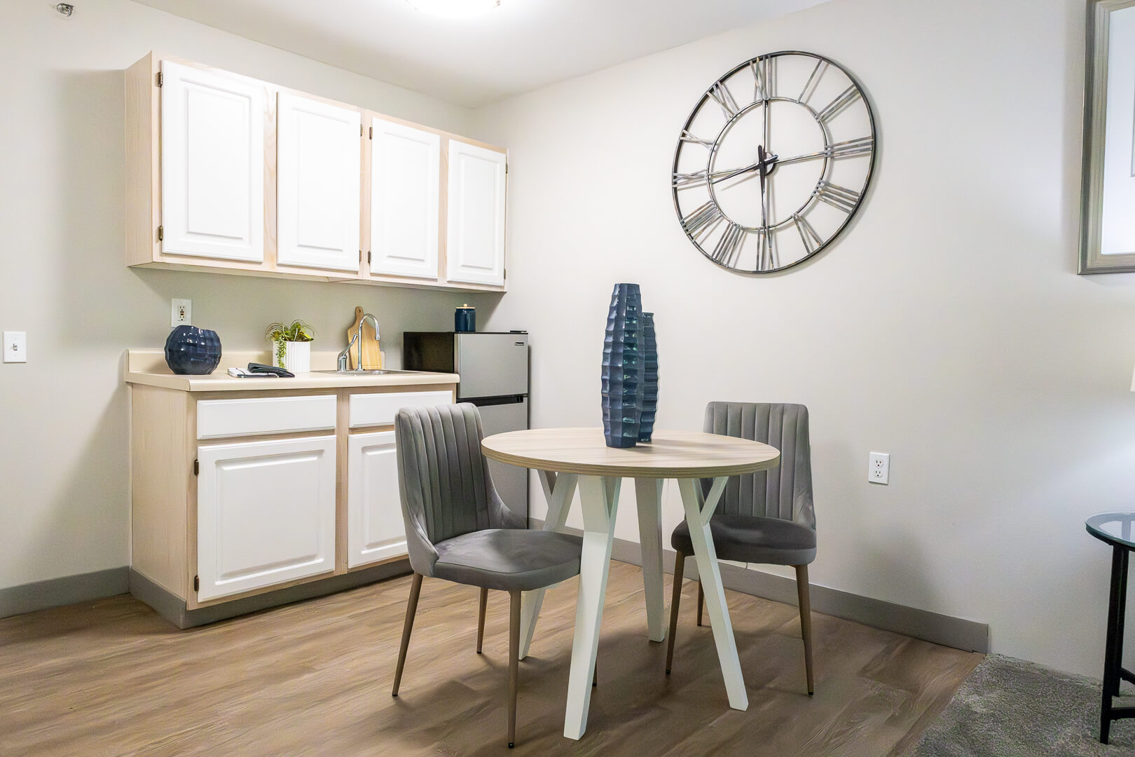Cozy Kitchenette with Dining Table and Wall Clock at an Independent Living Facility