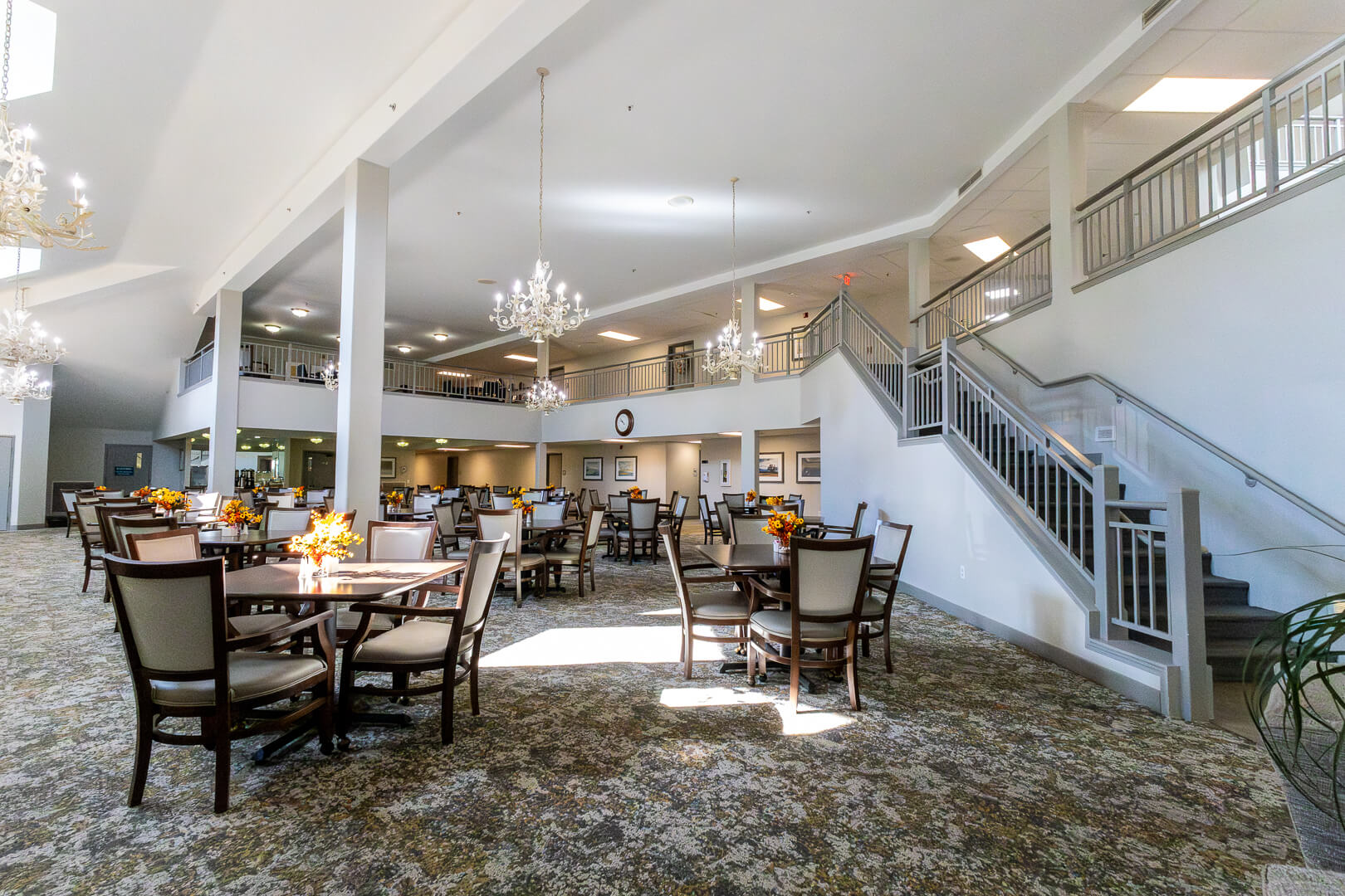 Elegant Dining Hall with Chandeliers and Grand Staircase at an Independent Living Community