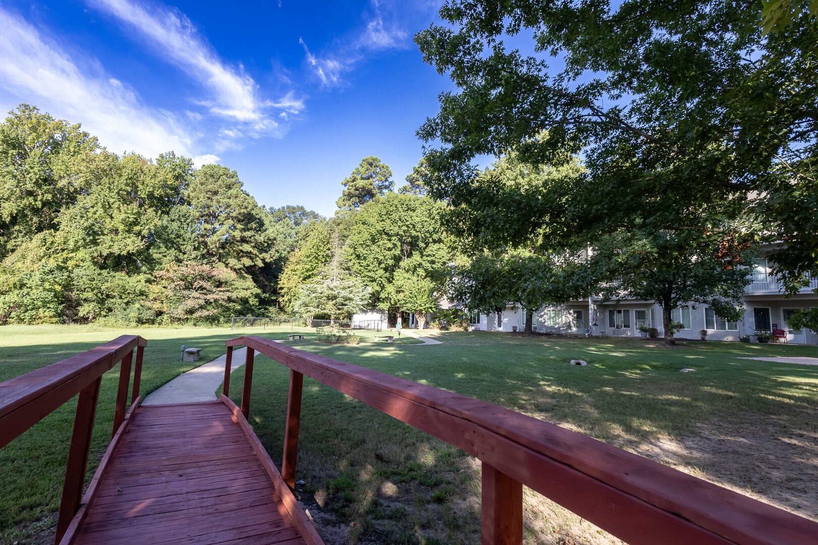 Wooden Footbridge Leading across a Green Lawn toward Residences at an Independent Living Facility