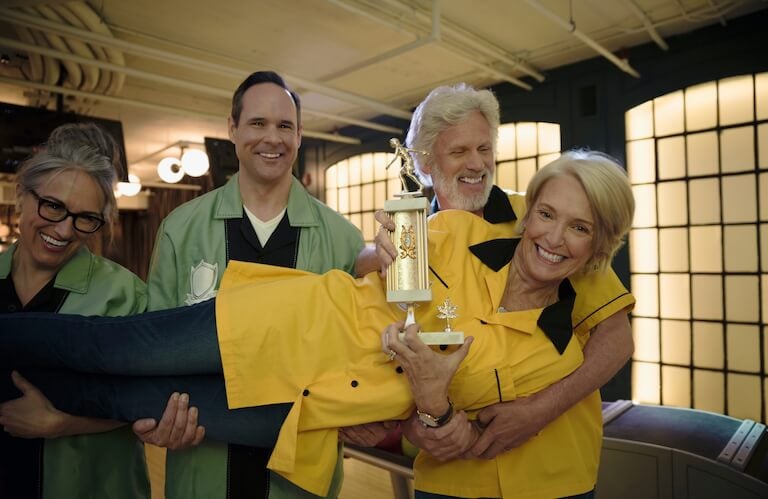 Group of Friends Holding a Woman with a Trophy Celebrating Together at an Independent Living Facility