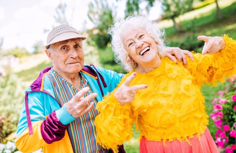 Colorfully Dressed Elderly Couple Posing Cheerfully Outdoors in the Garden at an Independent Living Community