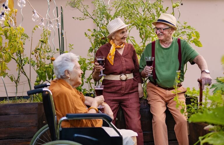 Elderly Friends Enjoying Wine Together in a Garden Setting at an Independent Living Community