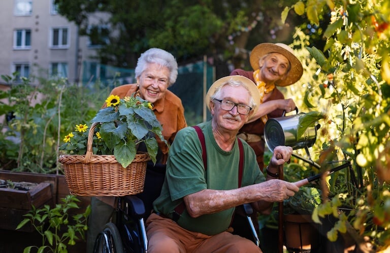 Elderly Friends Gardening Together with Flowers and Watering Can at an Independent Living Facility