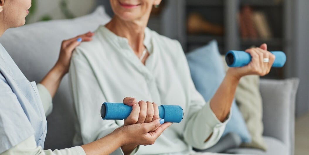 Nurse Guiding Elderly Woman Through Dumbbell Exercise at Independent Facility